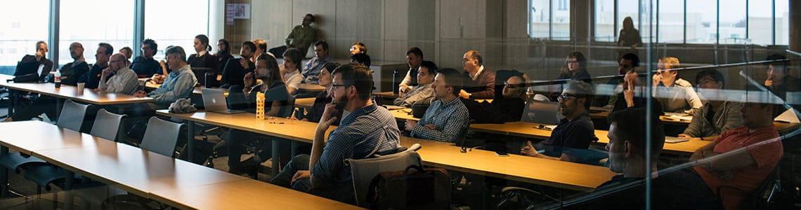 Academics seated at long tables during a lecture at the Kellogg Global Hub